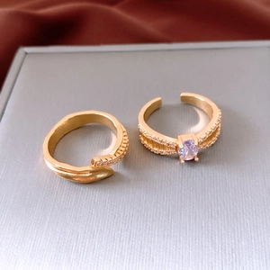Detail of two gold open rings with purple and clear oval zircon stones on a jewelry box