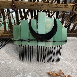 Detailed view of natural green stones and black moon charm on a metal bridal hair comb