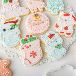 Pastel Christmas fondant cookies including snowman and tree on a white ceramic plate