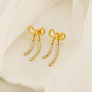 Elegant gold bow tassel earrings with sparkling rhinestones on a white shell tray