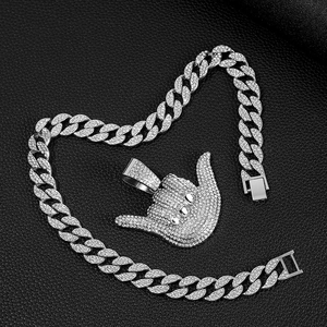 Silver 666 gesture pendant with cuban chain necklace laid in a heart shape on leather