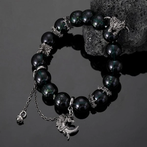 Detailed view of dark green beads with silver dragon head and crescent moon charms