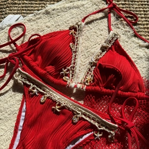 Detail of red bikini with shell starfish accents and crochet mesh skirt on beach towel