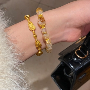 Detail of layered gold beaded bracelet and light yellow crystal bracelet on woman's wrist