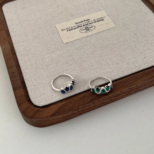 Detail of S925 silver rings with oval blue and green gemstones and side diamonds