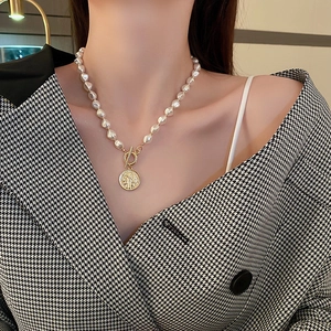 Detail view of pearl necklace with vintage portrait coin pendant and gold OT toggle clasp