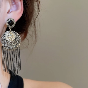 Detail of vintage coin earrings featuring black metal tassels and hollow round charms