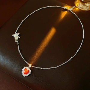 Close-up of heart red stone pendant necklace with unique silver hand charm and crystals