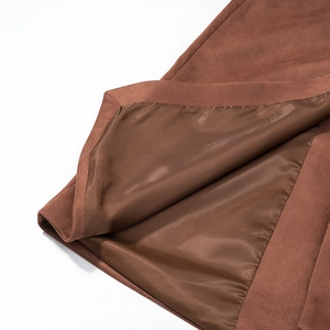 Détail d'un manteau en daim marron montrant la doublure en satin et les coutures