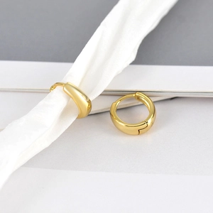 Minimalist gold hoop earrings with polished metal finish on elegant white silk background