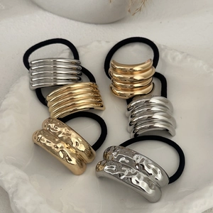 Close-up of gold and silver metallic ponytail holders with hammered and smooth textures