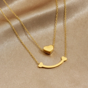 Collier double couche en acier doré avec pendentifs cœur et sourire sur fond de soie