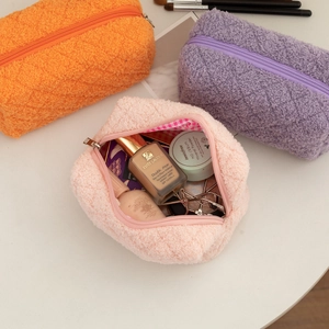 Detailed view of three large capacity teddy fleece makeup bags in soft pastel colors