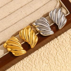 Symmetric wing texture stud earrings in gold and silver plating on jewelry display