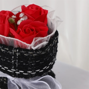 Detail of red soap rose bouquet wrapped in black tweed with white tulle and ribbon