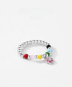 Macro detail of multicolored S925 silver beaded ring with floral charm in dopamine style