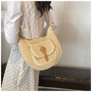 Detail of bohemian straw hobo bag with brown faux leather strap and golden rivet accents