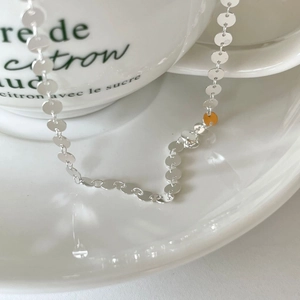 Detailed close-up of a 925 sterling silver disk choker necklace on a white ceramic cup