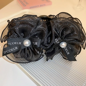 Gros plan sur une pince à cheveux fleur en organza noir avec perles sur un plateau chic