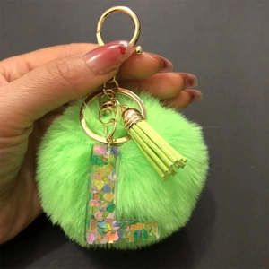Close-up of bright green fluffy pompom keychain with heart sequins and tassel detail