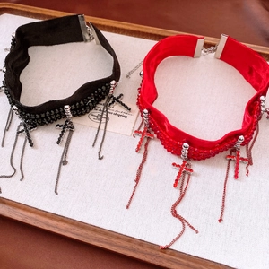 Détail de choker en velours avec croix en strass et pompons métalliques noir et rouge