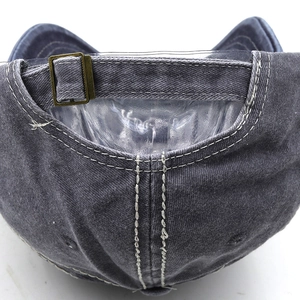 Close-up of the metal adjustable buckle and stitching on the vintage wash denim cap
