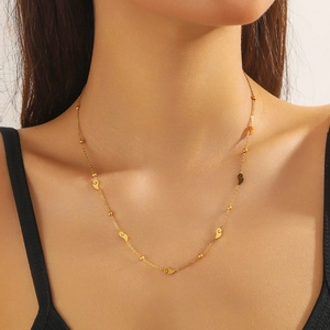 Detailed view of a gold stainless steel necklace with textured leaf pendants on model