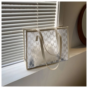 Close-up of transparent large PVC tote bag with white M-pattern and off-white trim detail