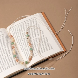 Detail of bohemian handmade woven bead belt in pink and green on an open book