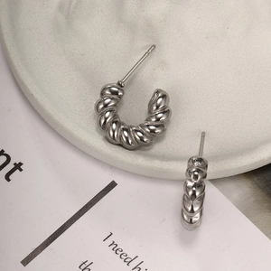 Close-up of silver C-shaped twist earrings with polished finish on a white tray