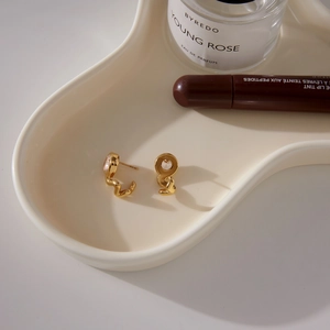 Elegant gold spiral C-shaped earrings with sparkling zircon on a white display tray