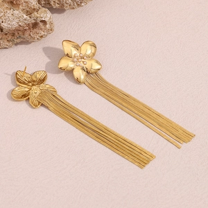 Detailed macro view of 18K gold plated flower stud earrings with elegant long chain tassels