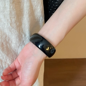 Détail d'un bracelet large en acrylique noir minimaliste avec une finition polie