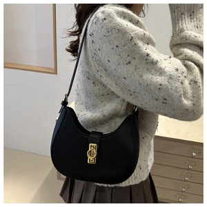 Close-up of black crescent shoulder bag featuring a sleek gold circular metal buckle