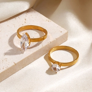 Golden minimalist ring set with marquise and round zircon stones on a silk fabric background