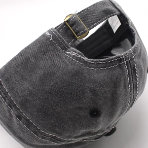 Close-up of adjustable metal buckle and wash label on dark grey washed cotton baseball cap