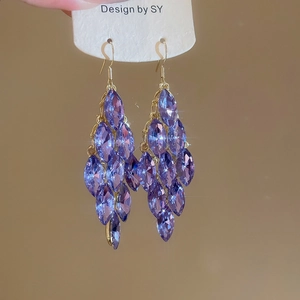 Detail of purple marquise-cut crystal leaf earrings with elegant gold tassel fringe
