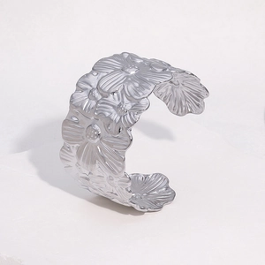 Macro detail of silver open cuff bracelet featuring continuous 3D embossed flower patterns