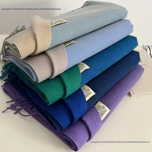 Close-up of multicolored double-sided cashmere-like scarves with fringe and woven labels