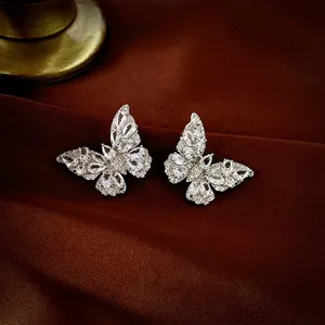 Elegant silver butterfly earrings with sparkling zircon stones on dark silk background