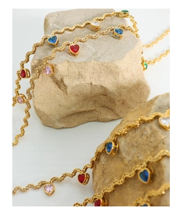 Detailed macro of gold twist chain necklace featuring colorful zircon heart pendants