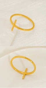 Detailed view of a gold cross ring on textured fabric with a minimalist jewelry display