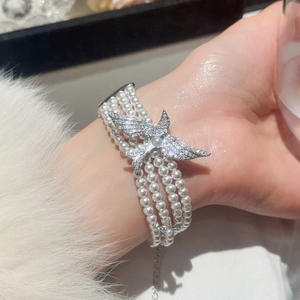 Vue macro d'un bracelet à trois rangs de perles avec un charmant oiseau en cristal brillant