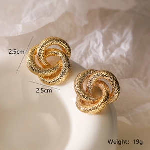 Vista detallada de pendientes geométricos de flor bañados en oro con diseño de nudo