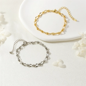 Dettaglio dei bracciali regolabili in oro e argento su un piatto di ceramica bianca