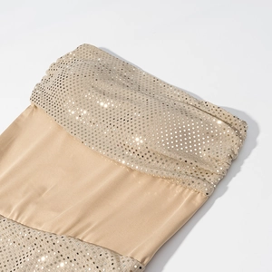 Gros plan sur les paillettes dorées champagne et le tissu élastique d'une robe de soirée chic