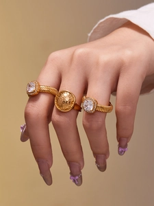 Détail de l'ensemble de trois bagues en acier doré 18 carats avec zircon carré