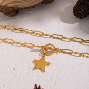 Classic gold star necklace with paperclip chain and T-bar clasp on a natural background