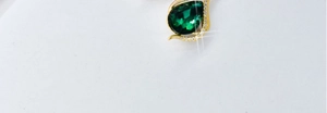 Detailed close-up of golden teardrop necklace with green gemstone and small crystals