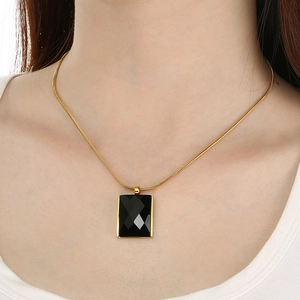 Detail of a vintage square black glass pendant on a gold snake chain necklace for women